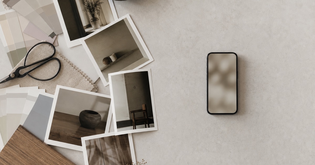 A desk split between a cluttered design workspace and a single clean smartphone