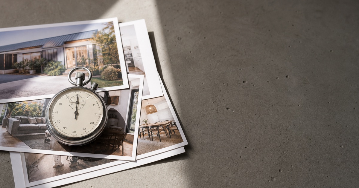 An analog stopwatch resting on a stack of printed listing photos